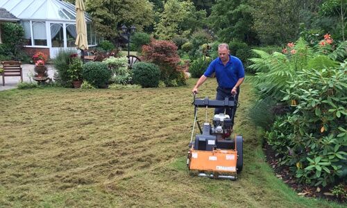 A technician using a machine to remove lawn thatch