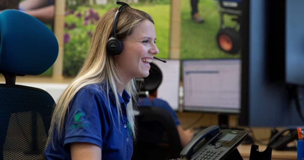 A lady smiling and answering the phone, in in Lawntech uniform