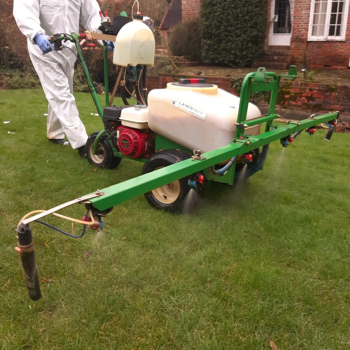 Technician driving a machine spraying herbicide onto a lawn